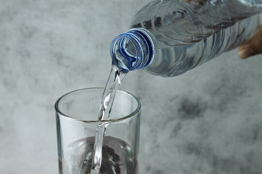 pouring water from bottle into glass on grey and texture background