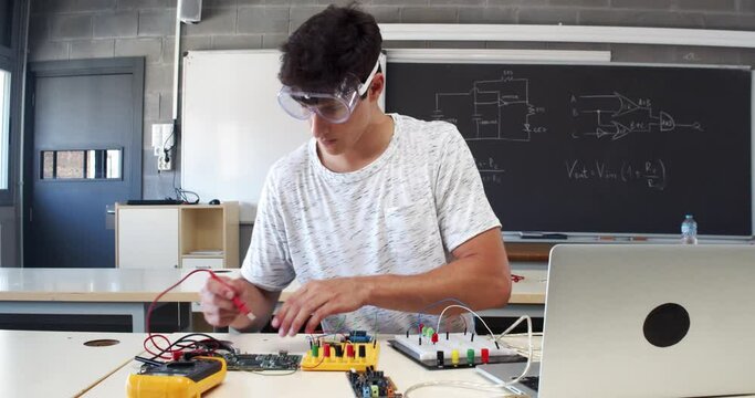 Young male student experimenting with electronic devices in the laboratory 