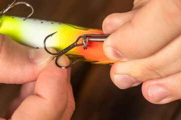 a man puts a baits hook on a wobbler, preparation for fishing, spinning, close-up