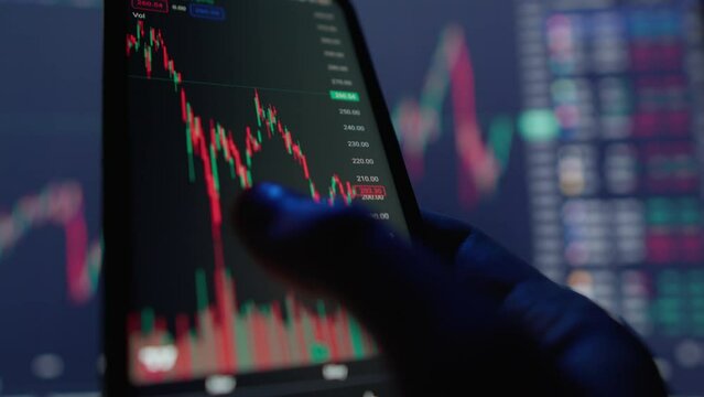 The investor analyzes trading data and charts on his smartphone to make smart financial movements, predict his profits and reduce possible risks and financial losses during a crisis and depression
