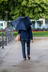 Rainy days: A female pedestrian walking along a promenade at a rainy day in summer outdoors