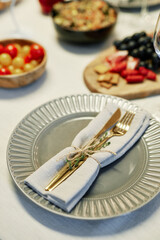 Focus on grey plate with folded cotton or linen napkin and fork with knife tied up with thread and...