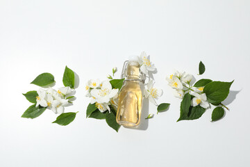 Jasmine flowers and glass bottle on white background, top view