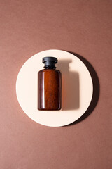 Cosmetic bottle with on the podium at brown background, Flat lay minimal ist composition for Bath ccosmetic products presentation