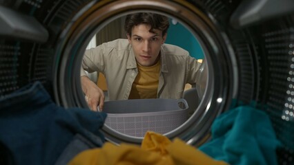 View from inside the washing machine, adult man with laundry basket takes out clothes from the drum