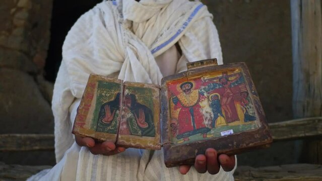 Ethiopian priest in Asheten mariam rock church holds icons Lalibela Ethiopia