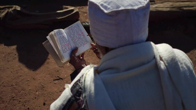 Priest praying with a bible Amhara Region Lalibela Ethiopia