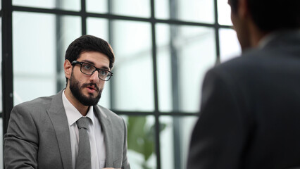 the manager receives a partner in his office sitting at the table