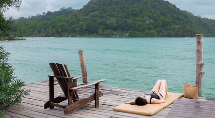 The woman is sunbathing by the sea.