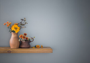 autumn flowers in rustic ceramic vase on background gray wall