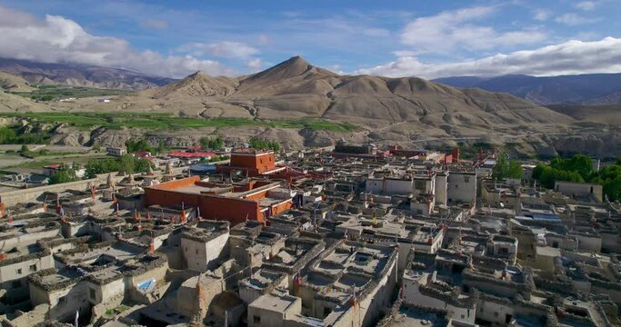 Drone shot of Lomanthang Upper Mustang Nepal which has beautiful inhabitation of people along with the landscapes and green tall trees. Buddhist flags waves in top of their building. 4K