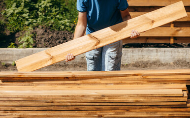 Adult man assembling a modern  wooden fence