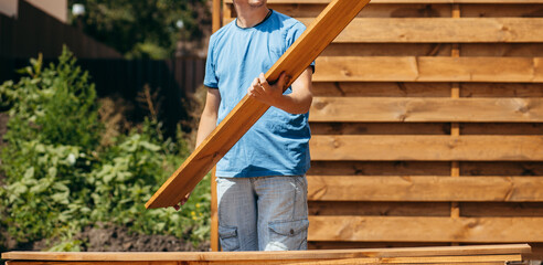 Adult man assembling a modern  wooden fence