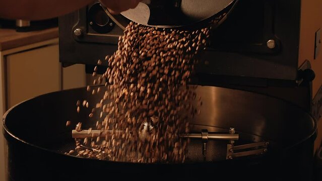 Production of fresh fried coffee beans. Roast master opens roasting coffee machine. Roasted coffee beans fall down on a cooling plate of an oven
