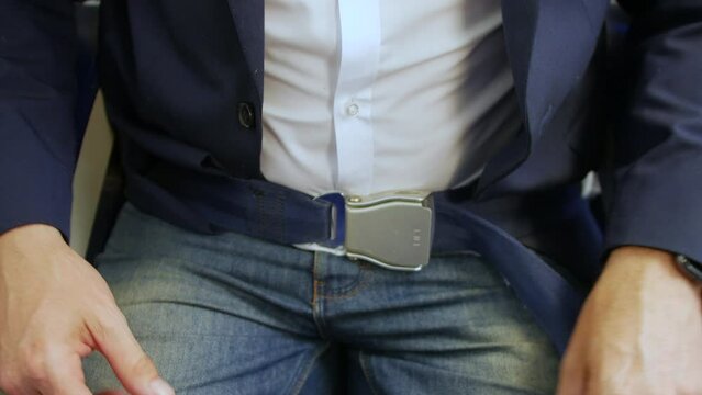 Man buckling and fastening seat belt on a passenger plane airliner seat