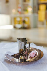 Water in a communion cup and other utensils at a catholic church prepared for the baptism of an infant