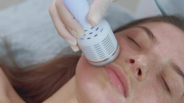 Close up footage of cosmetologist using cryotherapy lifting massage to restore and elevate patient's skin.