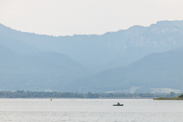 Fototapeta na wymiar Lonely fisherman in a small boat on the Chiemsee lake in Bavaria, Germany. 