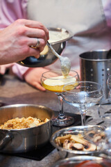 The process of making dessert. The cook's hand pours the cream into a glass dish