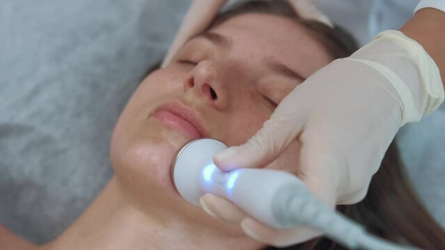 Footage of cosmetician makes ultrasound facial massage. Face beauty treatment.