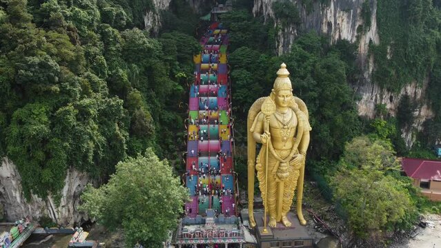 Aerial rotation shot of Batu Caves temple and the giant Murugan statue, Hindu God of war, in Kuala Lumpur, Malaysia.