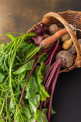 Basket with a harvest from the garden, beets and carrots with leaves, onions and potatoes