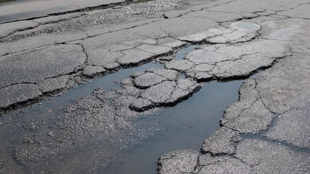 Potholes on bad asphalt road. Closeup. Nobody