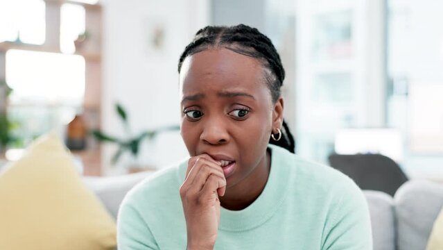 Anxiety, face and black woman. biting nails on a sofa for fear, worry or mental health crisis in her home. Stress, horror and African female in a living room nervous, abuse and depression ptsd trauma