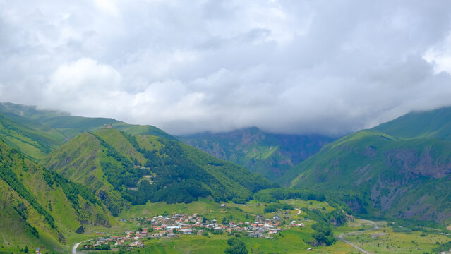 A View to Infinity: The Kazbegi Mountains Rise Above the Clouds, surrounding the small town of Kazbegi Mkinvartsveri in Georgia in a cloudy day in summer, Gudauri gergeti trinty church, ananuri