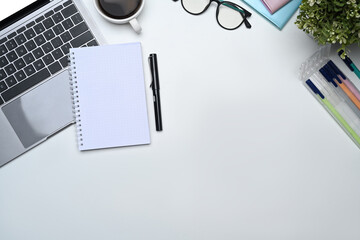Blank notepad, laptop, glasses, coffee cup and plant on white office. Copy space for your text