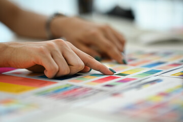 Closeup view female graphic designer working with color palette, choosing color samples for design project at modern office