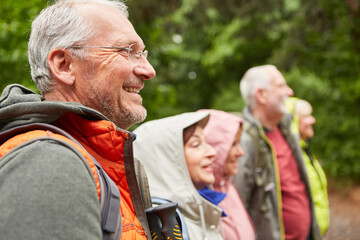 Senior man hiking with friends in forest during vacation