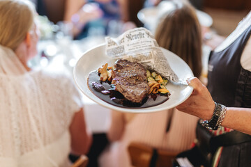 Waiter holding a delicious steak on a plate at a restaurant