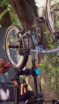 Vertical video Focused young black woman preparing necessary expert work tools for repairing broken bicycle parts. Sports-loving female aranging different professional equipment for servicing damaged