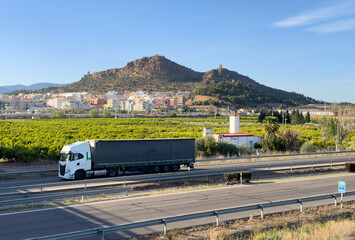Semi truck with Semi-trailer driving along highway. Goods Delivery by roads. Services and Transport logistics. Highway in Mountains landscape. Road traffic on motorway.