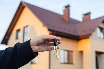 Hand holding key in front of home. Real estate, leasing insurance and purchase concept