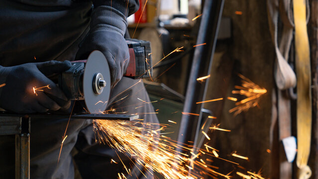 The man holds a flexi in his hands and cuts a metal plate