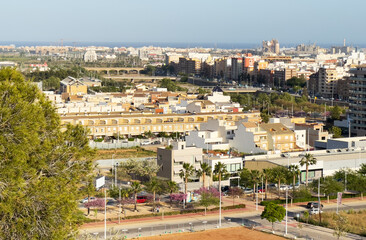 Fototapeta na wymiar Buildings and houses in city. Sagunto Town, view of city from mountain. Roofs of houses and townhouses roofs view from of Sagunto Castle, Spain. Background the Port of Sagunto and Mediterranean Sea.