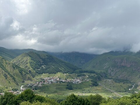 A View to Infinity: The Kazbegi Mountains Rise Above the Clouds, surrounding the small town of Kazbegi Mkinvartsveri in Georgia in a cloudy day in summer, Gudauri gergeti trinty church, ananuri