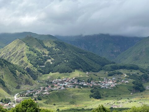 A View to Infinity: The Kazbegi Mountains Rise Above the Clouds, surrounding the small town of Kazbegi Mkinvartsveri in Georgia in a cloudy day in summer, Gudauri gergeti trinty church, ananuri