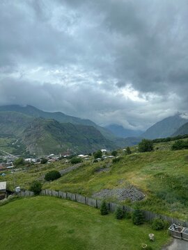 A View to Infinity: The Kazbegi Mountains Rise Above the Clouds, surrounding the small town of Kazbegi Mkinvartsveri in Georgia in a cloudy day in summer, Gudauri gergeti trinty church, ananuri