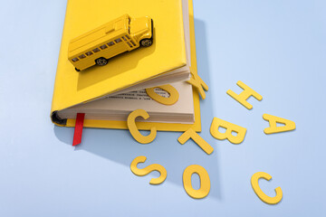 A yellow school bus drives over a book with large letters back to school. concept photo.