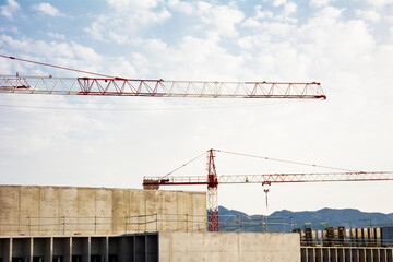 Building under construction with large tonnage cranes with the blue sky background