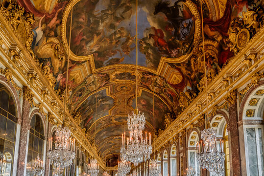 Versailles, France - April 9th, 2022: Ornate interior and the painted ceiling of the Hall of Mirrors inside of the Versailles Palace in Versailles, France.