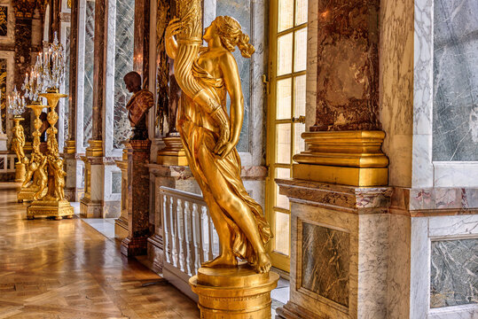 Versailles, France - April 9th, 2022: Golden statues and marble columns of the Hall of Mirrors inside of the Versailles Palace in Versailles, France.