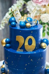 A beautiful large cake of blue and gold color for a man or woman 20 years old.