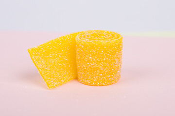 Yellow jelly candy on a pastel pink background.