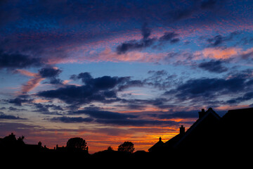 Sunset in Norfolk, United Kingdom.  Gold and blue sky over rooftops. 