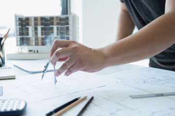 Engineer working and drawing on blueprint using compass.