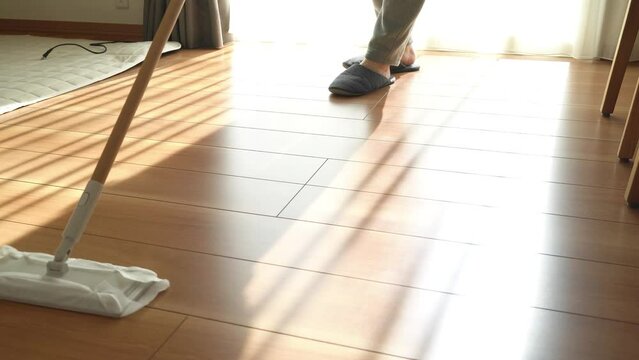 モップで床を掃除する男性